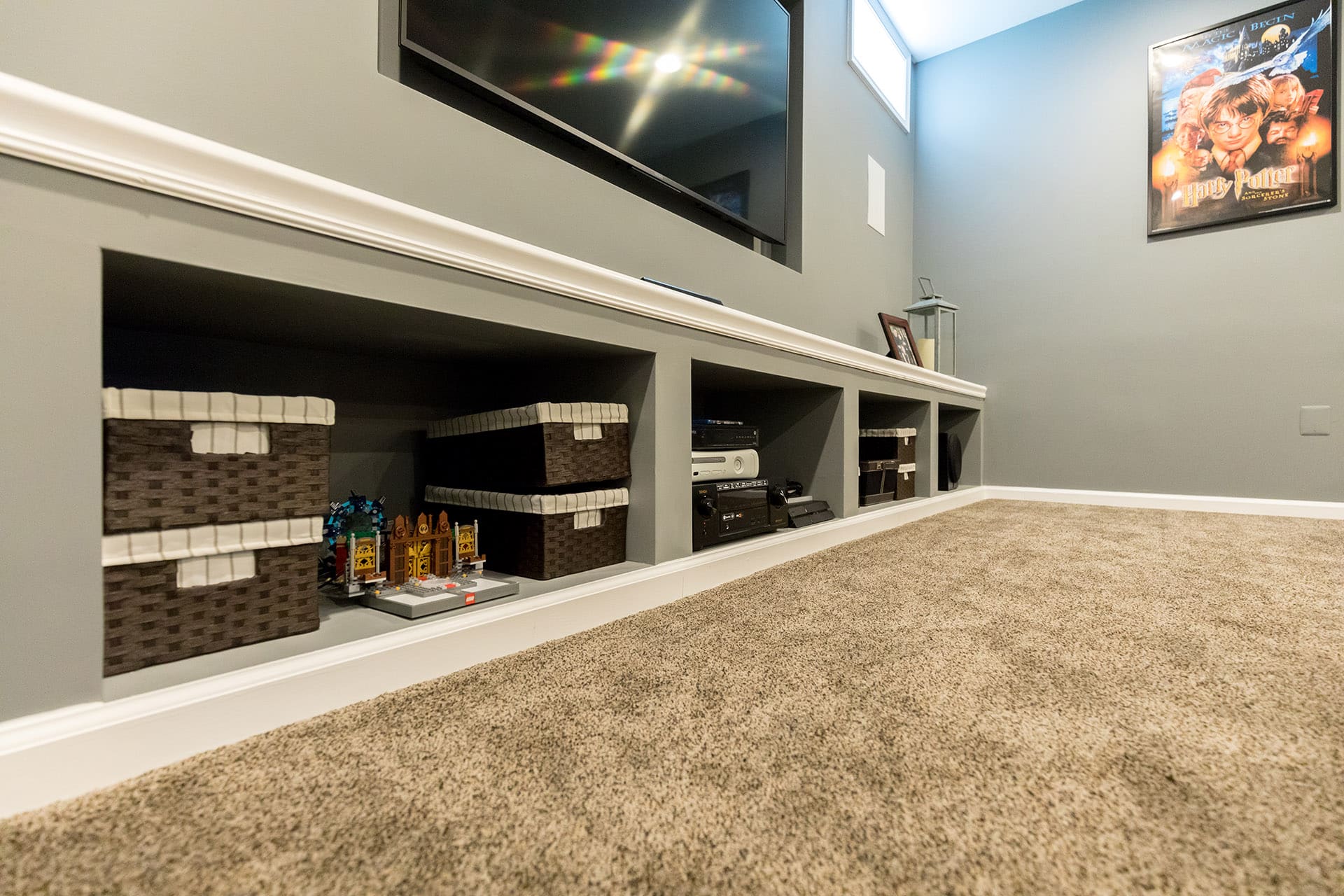 Basement media wall with built-in storage cubbies by GBC Kitchen & Bath
